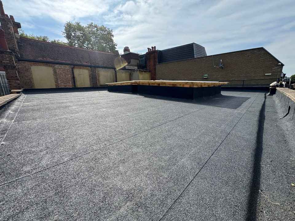 A finished torch-on felt roof with two rooflight kerbs, dressed up to the parapets.